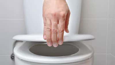 hand of a man closing the lid of a toilet