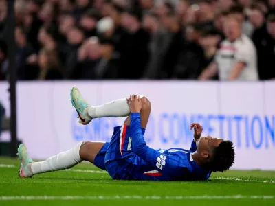 Chelsea's Estevao holds his leg after picking up an injury during the English Premier League soccer match in London, Saturday April 18, 2026. (John Walton/PA via AP)