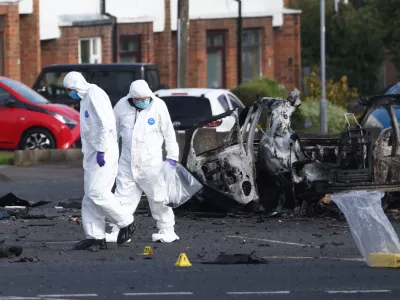 Forensic investigators inspect the site of a car bomb that exploded outside Dunmurry police station in South Belfast, Sunday, April 26, 2026. (AP Photo/Peter Morrison)