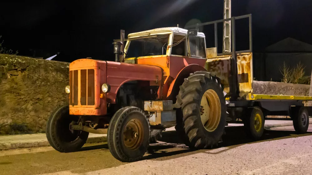 Night photograph of an old red tractor under artificial lighting.