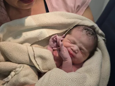 In this photo provided by Tina Fritz, Ashley Blair holds her daughter Brielle, who was born April 24, 2026, on a Delta Air Lines flight just as it was landing in Portland, Ore. (Tina Fritz via AP)