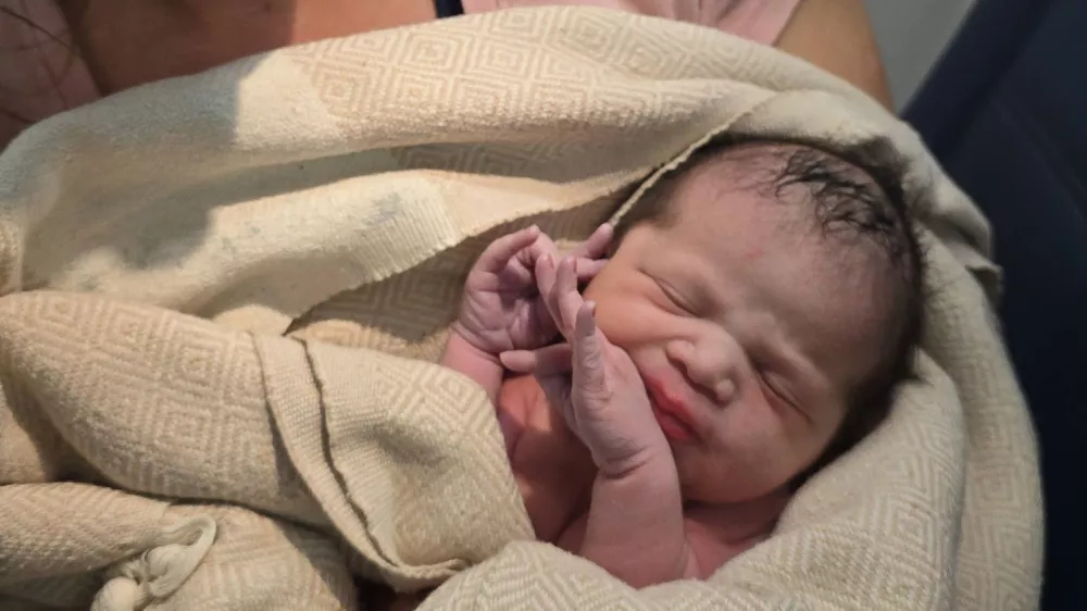 In this photo provided by Tina Fritz, Ashley Blair holds her daughter Brielle, who was born April 24, 2026, on a Delta Air Lines flight just as it was landing in Portland, Ore. (Tina Fritz via AP)