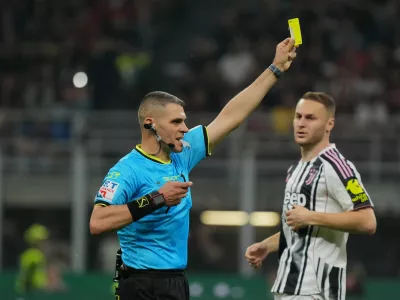 Referee Simone Sozza shows the yellow card during the Serie A soccer match between AC Milan and Juventus, in Milan, Italy, Sunday, April 26, 2026. (Alessio Morgese/LaPresse via AP)