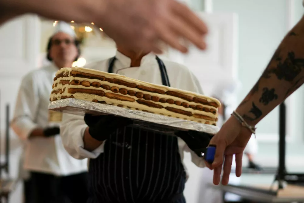Chefs and volunteers help carry parts of a tiramisu during preparations for their attempt to break the Guinness World Record for the longest tiramisu, with the dessert expected to exceed 300 metres, in London, Britain, April 26, 2026. REUTERS/Carlos Jasso