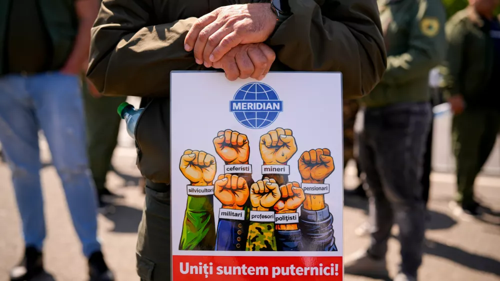 A man rests his hands on a placard reading "United we're strong! Solidarity" during a protest staged by multiple unions demanding the Government's resignation following measures in areas like taxation, work legislation and social security, outside the Government headquarters in Bucharest, Romania, Tuesday, April 28, 2026. (AP Photo/ Vadim Ghirda)