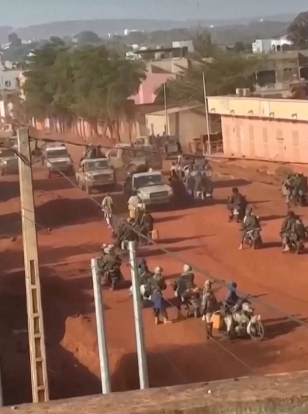 Vehicles move through a group of armed men on motorbikes standing on a street in Kati, near the capital city Bamako, Mali, in this screengrab obtained from a social media video released on April 25, 2026. Social Media/Reuters TV via REUTERS. NO RESALES. NO ARCHIVES.  Verfication lines: Buildings, road layout, foliage and hills match satellite imagery. Date could not be verified, however, Mali's army said unidentified groups attacked several positions in the capital and elsewhere in the country on April 25. No older versions of the video could be found posted online before April 25.