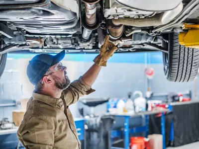 Professional Caucasian Mechanic Standing Under the Vehicle Lifted on Car Lift Checking the Condition of Catalytic Converter. Automotive Theme. / Foto: Istockphoto