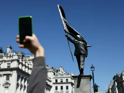A person takes a picture of statue, depicting a figure carrying a flag covering their face and stepping off a plinth, by British street artist Banksy in London, Britain, May 1, 2026. REUTERS/Jack Taylor