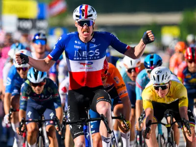 Dorion Godon, center, from France, raises his arms after crossing the finish line to win the third stage, a 176,6 km race around Orbe at the 79th Tour de Romandie UCI World Tour Cycling race, in Orbe, Switzerland, Friday, May 1, 2026. (Jean-Christophe Bott/Keystone via AP)