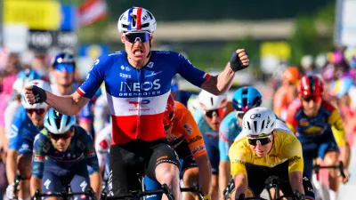 Dorion Godon, center, from France, raises his arms after crossing the finish line to win the third stage, a 176,6 km race around Orbe at the 79th Tour de Romandie UCI World Tour Cycling race, in Orbe, Switzerland, Friday, May 1, 2026. (Jean-Christophe Bott/Keystone via AP)
