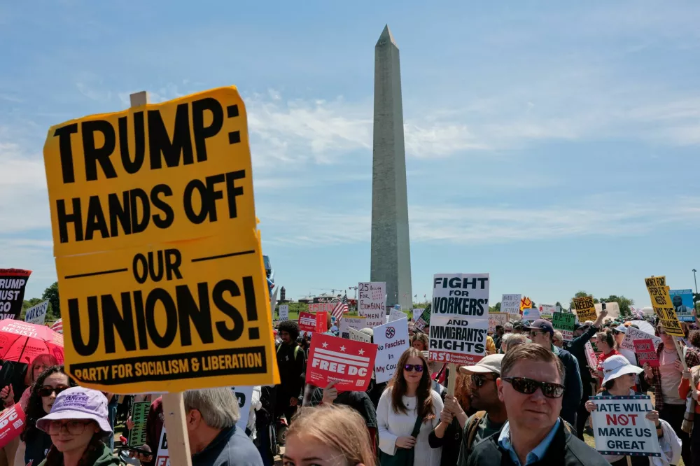 Demonstrators hold placards during a May Day march and rally, with the Washington Monument in the background, in Washington, D.C., U.S., May 1, 2026. REUTERS/Kylie Cooper