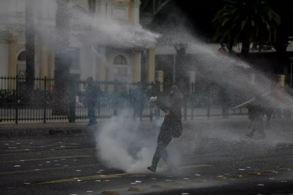 A demonstrator throws an object while getting sprayed by a water cannon during clashes at a May Day rally in Santiago, Chile, May 1, 2026. REUTERS/Pablo Sanhueza