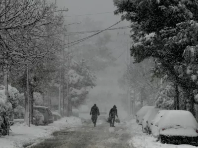 15 February 2021, Greece, Athens: People walk in a street covered with snow after strong winds and heavy snowfalls caused by the Medea storm which hit Greece. Photo: -/Eurokinissi via ZUMA Wire/dpa