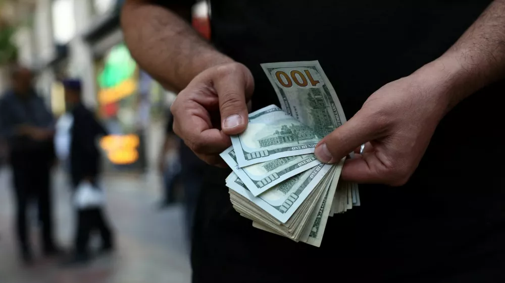 A currency dealer holds one-hundred-dollar bills, as the value of the Iranian rial drops, in Tehran, Iran, May 2, 2026. Majid Asgaripour/WANA (West Asia News Agency) via REUTERS ATTENTION EDITORS - THIS PICTURE WAS PROVIDED BY A THIRD PARTY