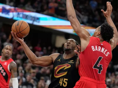 Cleveland Cavaliers guard Donovan Mitchell (45) goes up for a shot next to Toronto Raptors forward Scottie Barnes (4) in the second half in Game 7 of a first-round NBA basketball playoffs series in Cleveland, Sunday, May 3, 2026. (AP Photo/Sue Ogrocki)