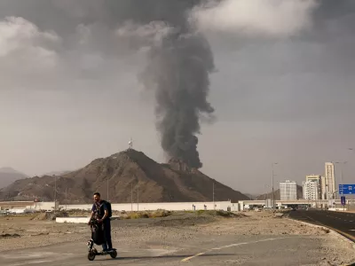 FILE PHOTO: A person rides on a scooter as smoke rises in the Fujairah oil industry zone following a fire caused by debris after interception of a drone by air defenses, in Fujairah, United Arab Emirates, March 3.  REUTERS/Amr Alfiky/File Photo