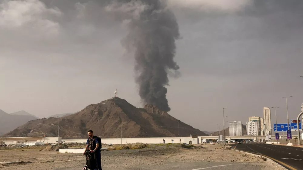 FILE PHOTO: A person rides on a scooter as smoke rises in the Fujairah oil industry zone following a fire caused by debris after interception of a drone by air defenses, in Fujairah, United Arab Emirates, March 3.  REUTERS/Amr Alfiky/File Photo