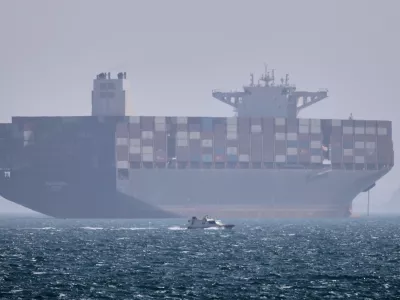 A container ship sits at anchor as a small motorboat passes in the foreground in the Strait of Hormuz off Bandar Abbas, Iran, Saturday, May 2, 2026. (Amirhosein Khorgooi/ISNA via AP)