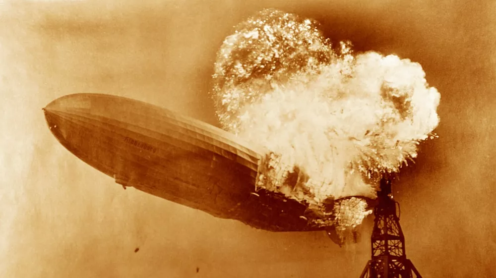 Hindenburg disaster, coloured image. View of the German airship Hindenburg (LZ 129) on fire over Naval Air Station (NAS) Lakehurst, New Jersey, USA, on 6th May 1937. This airship is famous for the Hindenburg disaster of 6th May 1937, when it caught fire and was destroyed during its attempt to dock with its mooring mast at NAS Lakehurst. Of the 97 crew and passengers on board 35 were killed, along with one member of the ground crew. The balloon was filled with hydrogen, a highly flammable gas. The cause of the accident has never been established but the disaster destroyed public confidence and marked the abrupt end of the airship era. Here the ships water ballast tanks (black dots, lower centre-left) can be seen falling.,Image: 270936545, License: Rights-managed, Restrictions:, Model Release: no