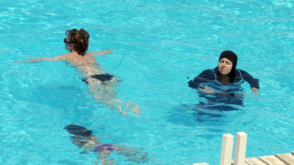 A woman wearing a swimming outfit that covers her body swims at the pool of a hotel in the Tunisian coastal holiday city of Mahdia, on August 31, 2012. According to some local media, fewer women go to the beach wearing bikinis as they fear attacks by religious extremists after the Islamist Ennahda party came to power following the uprising which toppled president Zine el Abidine Ben Ali.,Image: 140650482, License: Rights-managed, Restrictions:, Model Release: no