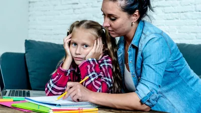 Mother becoming frustrated with daughter whilst doing homework sitting on sofa At home in learning difficulties homework parenting and education concept
