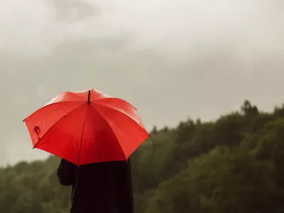 Man with red umbrella standing lonely in the rain and getting drenched / Foto: Stevanovicigor