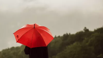 Man with red umbrella standing lonely in the rain and getting drenched / Foto: Stevanovicigor