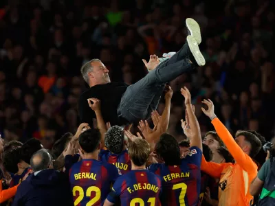 Barcelona head coach Hansi Flick is lifted by his players after winning the Spanish La Liga soccer match against Real Madrid to clinch the Spanish league title in Barcelona, Spain, Sunday, May 10, 2026. (AP Photo/Joan Monfort)