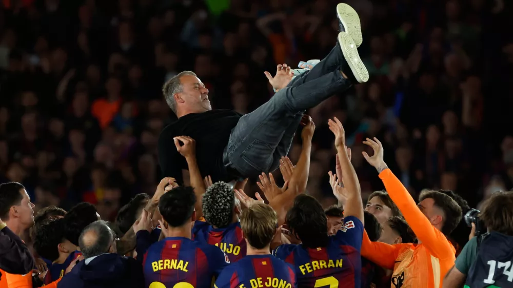 Barcelona head coach Hansi Flick is lifted by his players after winning the Spanish La Liga soccer match against Real Madrid to clinch the Spanish league title in Barcelona, Spain, Sunday, May 10, 2026. (AP Photo/Joan Monfort)