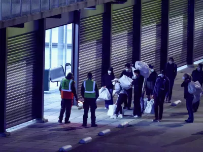Passengers evacuated from the cruise ship MV Hondius, which was affected by a hantavirus outbreak, carry their belongings after disembarking at Eindhoven Air Base, Netherlands, May 12, 2026. REUTERS/Piroschka van de Wouw