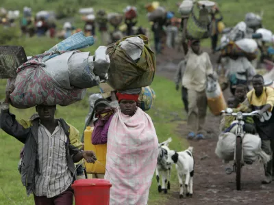 People carry their belongings as they flee fighting, near Kibumba, some 40 kilometers (25 miles) north of Goma, in eastern Congo, Monday, Oct. 27, 2008. Thousands of refugees and soldiers are fleeing fighting in eastern Congo in what appears to be a major retreat of government forces being attacked by rebels of renegade Gen. Laurent Nkunda. (AP Photo/Karel Prinsloo)
