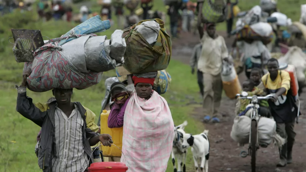People carry their belongings as they flee fighting, near Kibumba, some 40 kilometers (25 miles) north of Goma, in eastern Congo, Monday, Oct. 27, 2008. Thousands of refugees and soldiers are fleeing fighting in eastern Congo in what appears to be a major retreat of government forces being attacked by rebels of renegade Gen. Laurent Nkunda. (AP Photo/Karel Prinsloo)
