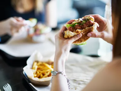 woman eating eating vegan meatless burger in restaurant during the day