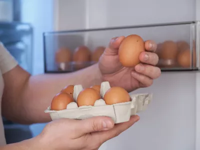 Close up of a man putting fresh eggs into refrigerator.