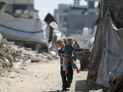 A Palestinian boy, carrying a girl child, walks through a damaged area amid the rubble of residential buildings in Gaza City, May 11, 2026. REUTERS/Dawoud Abu Alkas   TPX IMAGES OF THE DAY / Foto: Dawoud Abu Alkas