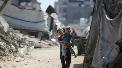 A Palestinian boy, carrying a girl child, walks through a damaged area amid the rubble of residential buildings in Gaza City, May 11, 2026. REUTERS/Dawoud Abu Alkas   TPX IMAGES OF THE DAY / Foto: Dawoud Abu Alkas