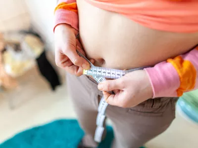 woman measures her abdomen with a measuring tape