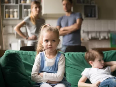 Frustrated kid girl feels upset, offended or bored ignoring avoiding worried parents and brother, little sad sister not talking to child boy after fight sulking sitting on couch, siblings rivalry