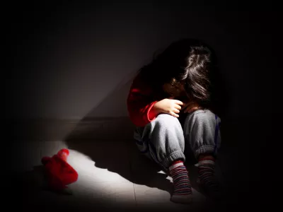young girl sitting down alone in the dark.