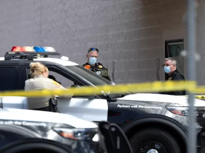 Las Vegas Metropolitan Police crime scene analysts and a Metro Police officer, left, work outside a Smith's supermarket in Las Vegas, after a reports of a shooting on Tuesday, May 12, 2026. (Steve Marcus/Las Vegas Sun via AP)