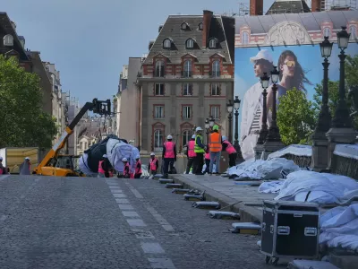 Workers continue preparations on the wrapped Pont Neuf bridge project, titled Pont Neuf Cavern, by French artist JR, in Paris, Saturday, May 16, 2026, ahead of its inauguration on June 6. (AP Photo/Michel Euler)