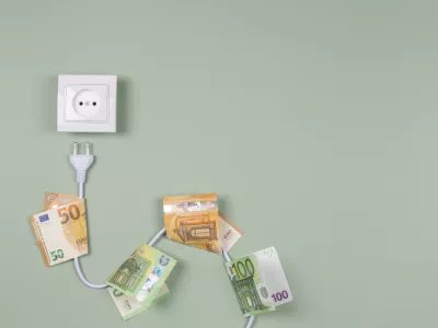 Electric power plug with euro banknotes on it and electric socket on light green background. Electricity cost and expensive energy concept.