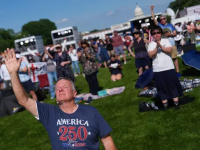 Teddy May, from Mobile, Alabama, kneels while worshiping during Rededicate 250, a mostly conservative Christian prayer gathering in honor of the United States' 250th anniversary, on the National Mall, Sunday, May 17, 2026, in Washington. (AP Photo/Julia Demaree Nikhinson)
