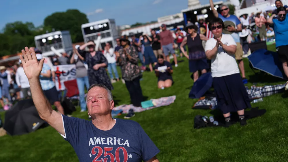 Teddy May, from Mobile, Alabama, kneels while worshiping during Rededicate 250, a mostly conservative Christian prayer gathering in honor of the United States' 250th anniversary, on the National Mall, Sunday, May 17, 2026, in Washington. (AP Photo/Julia Demaree Nikhinson)