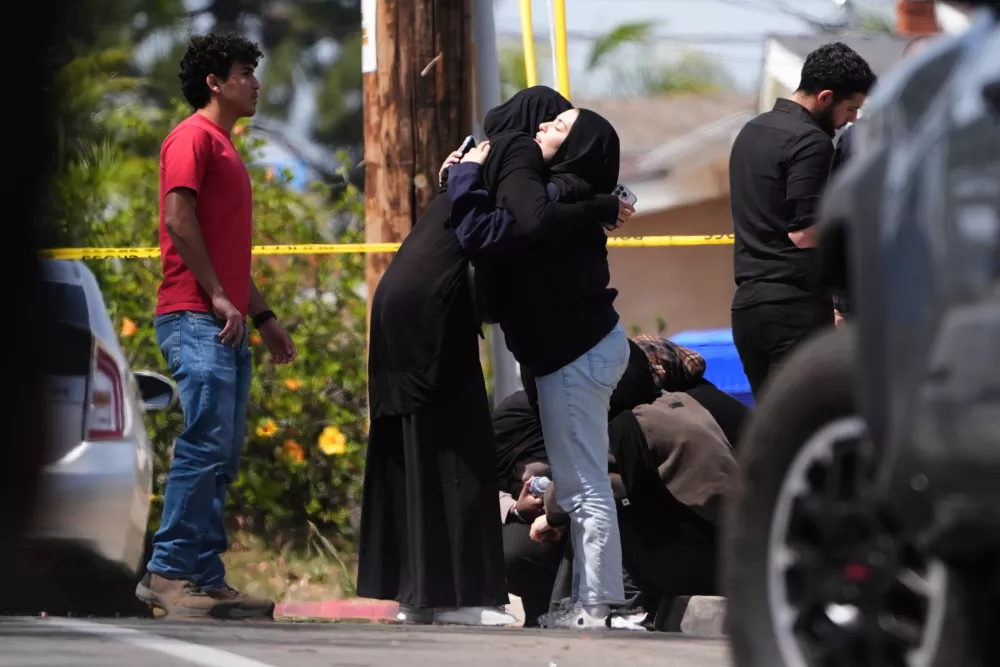 People embrace near the scene of a shooting outside the Islamic Center of San Diego Monday, May 18, 2026, in San Diego. (AP Photo/Gregory Bull)
