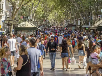 Barcelona, Spain - July 5, 2016: Hundreds of people promenading in the busiest street of Barcelona, the Ramblas. The street extends 1.2 kilometers connects the Placa de Catalunya in the centre with the Christopher Columbus Monument at Port Vell.