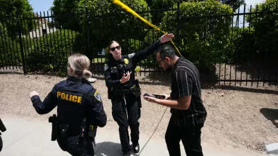 People walk under police tape at the scene of a shooting outside the Islamic Center of San Diego Monday, May 18, 2026, in San Diego. (AP Photo/Gregory Bull)