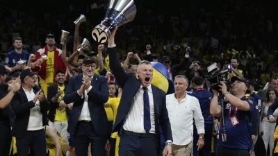 Fenerbahce's head coach Saras Jasikevicius holds the trophy as they celebrate winning the Euroleague final basketball match between Monaco and Fenerbahce in Abu Dhabi, United Arab Emirates, Sunday, May 25, 2025. (AP Photo/Altaf Qadri)