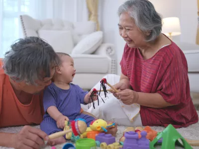 Grandparents and their little grandchild play happily in the living room of the house