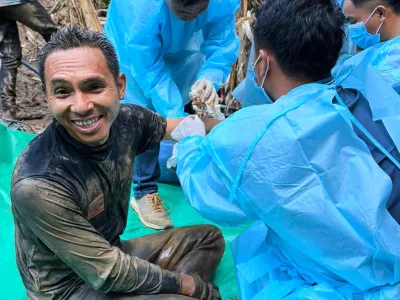 In this image released by Metta Tham Rescue Kalasin, rescuers, left, sit after rescuing people who have been trapped in a cave in Xaisomboun province, Laos. Wednesday, May 27, 2026. (Metta Tham Rescue Kalasin via AP)